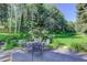 Outdoor living space featuring a stone patio, lush lawn, and mature trees at 4241 S Meadow Brook Ln, Evergreen, CO 80439