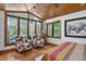 Bright bedroom showcasing two cow print chairs and large windows providing scenic wooded views at 4241 S Meadow Brook Ln, Evergreen, CO 80439