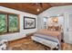 Bedroom features a colorful quilt bed, wooden floors, buffalo art, and a window with wooded views at 4241 S Meadow Brook Ln, Evergreen, CO 80439