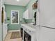 Bright laundry room with sink, white cabinets, washer, dryer, and a window overlooking the greenery at 4241 S Meadow Brook Ln, Evergreen, CO 80439