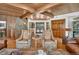 Cozy living room featuring a stone wall, wood ceiling, and beautiful natural light at 4241 S Meadow Brook Ln, Evergreen, CO 80439