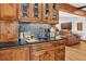 Wet bar with wood cabinets, mosaic tile backsplash, and access to living room at 4241 S Meadow Brook Ln, Evergreen, CO 80439