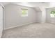 A bright bedroom has neutral walls, cozy carpet, and two windows providing natural light at 1856 S Monroe St, Denver, CO 80210
