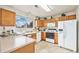 Well-lit kitchen featuring wood cabinets, white appliances, and a window overlooking the yard at 4710 N Foxtail Dr, Castle Rock, CO 80109