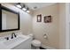 Powder room features a white vanity, dark fixtures, and decorative wall art at 23 Honey Locust, Littleton, CO 80127