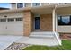 Inviting front entrance with brick accents, concrete steps, a blue door, and an attached two car garage at 23 Honey Locust, Littleton, CO 80127