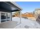 Back patio with snow-covered yard and wood fence under a bright blue sky at 14441 E 102Nd Ave, Commerce City, CO 80022