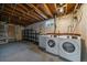 Unfinished basement laundry room with washer, dryer, shelving, and exposed ceiling at 6026 Iris Way, Arvada, CO 80004