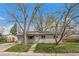 Charming single-story home with a well-maintained front yard and solar panels under the shade of mature trees at 6026 Iris Way, Arvada, CO 80004