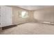 A bright living room boasts neutral paint, plush carpet, and large window at 6131 Wolff St, Arvada, CO 80003