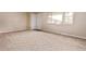 A bright living room boasts neutral paint, plush carpet, and large window near the door at 6131 Wolff St, Arvada, CO 80003