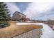 Expansive backyard with partial snow cover, a well-maintained lawn, and a charming fence line at 15640 Agate Creek Dr, Monument, CO 80132