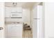 Compact kitchen features white cabinets and appliances with an adjacent carpeted staircase at 2773 S Franklin St, Denver, CO 80210