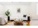 A bright living room with hardwood floors, a white couch, and a round wood coffee table at 2773 S Franklin St, Denver, CO 80210