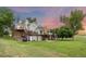 Backyard view of a two-story home with multiple decks, brick chimney, lawn, and mature trees at 7883 S Espana Way, Centennial, CO 80016