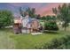 Rear exterior of the home with multiple decks, well-maintained lawn, mature trees, and vibrant sunset at 7883 S Espana Way, Centennial, CO 80016