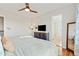 Bright bedroom featuring wood floors, a ceiling fan, with bathroom entrance and storage console at 9144 Roadrunner St, Highlands Ranch, CO 80129