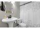 A neutral bathroom featuring a pedestal sink, toilet and shower with decorative shower curtain at 8660 De Soto St, Denver, CO 80229