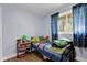 A colorful bedroom with wood floors, a window and blue curtains at 8660 De Soto St, Denver, CO 80229