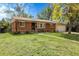 Inviting single-story brick home with a lush green lawn, mature tree, and attached garage at 8660 De Soto St, Denver, CO 80229
