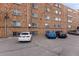 View of the parking lot behind a brick apartment building at 1350 Josephine St # 208, Denver, CO 80206