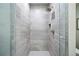 Modern bathroom shower with gray stone-look tile, a built-in niche, and a glass door at 4625 W 50Th Ave # 309, Denver, CO 80212