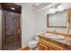Bathroom includes shower with tile surround, vanity with tile countertop, wood cabinets, sink and large mirror at 10448 Kicking Horse Dr, Littleton, CO 80125