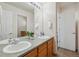 Bathroom with double sinks, wood cabinets, a large mirror, and a door to an adjoining room at 10448 Kicking Horse Dr, Littleton, CO 80125