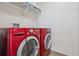 Bright laundry room features a red front-load washer and dryer, with white shelving for storage at 10448 Kicking Horse Dr, Littleton, CO 80125