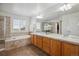Bright primary bathroom featuring dual sinks, a soaking tub, and a separate shower at 10448 Kicking Horse Dr, Littleton, CO 80125