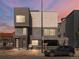 Modern gray three-story townhouse with a car parked in front at dusk at 4917 Lowell Blvd # 105, Denver, CO 80221