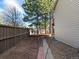 Side yard bordered by a wooden fence and mature trees and side of home at 6583 W Gould Dr, Littleton, CO 80123