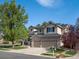 Beautiful two-story home with a three-car garage, brick detailing, lush lawn, and mature trees in a desirable neighborhood at 6583 W Gould Dr, Littleton, CO 80123