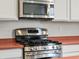 Close up on the stainless steel range with microwave, white cabinets, and unique, colored counter tops at 6583 W Gould Dr, Littleton, CO 80123