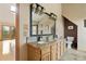 Bright bathroom features a granite countertop, wood cabinets, and a large mirror with decorative lighting at 13452 Riley Peak Rd, Conifer, CO 80433