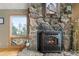 Close-up view of a cozy stone fireplace with a modern iron insert at 13452 Riley Peak Rd, Conifer, CO 80433