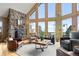 Bright living room boasts soaring windows, hardwood floors, stone fireplace and ample seating at 13452 Riley Peak Rd, Conifer, CO 80433