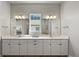 Spacious bathroom featuring dual sinks, white cabinetry, and a large mirror at 3293 Offbeaten Pl, Castle Rock, CO 80108