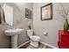 Stylish powder room featuring a pedestal sink, decorative mirror, and vibrant red accent cabinet at 2511 Loon Ln, Castle Rock, CO 80104