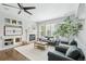 Bright living room with a fireplace, built-in shelving, ceiling fan, and large windows with plantation shutters at 17020 E 107Th Ave, Commerce City, CO 80022