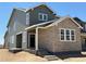 Side view of a two-story home featuring a stone and siding exterior, complemented by a covered porch at 3295 N Coolidge Way, Aurora, CO 80019