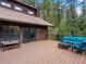 A spacious wooden deck with outdoor seating nestled in a serene backyard surrounded by trees at 28272 Shadow Mountain Dr, Conifer, CO 80433