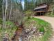 Charming creek-side view of a two-story home surrounded by a forest at 28272 Shadow Mountain Dr, Conifer, CO 80433