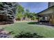Spacious, well-manicured backyard featuring a lush lawn, mature trees and a charming stone retaining wall at 8043 S Zephyr St, Littleton, CO 80128