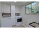Bright laundry room with modern washer and dryer, white cabinets, and a window overlooking the backyard at 8043 S Zephyr St, Littleton, CO 80128
