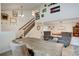 Open-concept living room with vaulted ceilings, wooden staircase, and multiple seating areas with natural light at 8043 S Zephyr St, Littleton, CO 80128