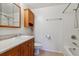 Bright bathroom featuring a vanity with oak cabinets, white fixtures, and tiled shower at 1231 Missouri Ave, Longmont, CO 80501