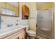 Bright bathroom featuring a vanity with oak cabinets, white fixtures, and glass shower at 1231 Missouri Ave, Longmont, CO 80501