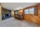 A cozy living room featuring carpet, wood-paneled walls, and a stone fireplace at 1231 Missouri Ave, Longmont, CO 80501