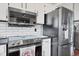 Close up of kitchen appliances, including stainless refrigerator, microwave and stove, with subway tile backsplash at 18200 E Asbury Pl, Aurora, CO 80013